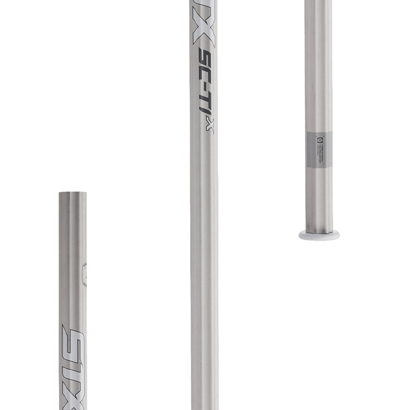 Three STX HE AAX0 64/BK/BOM lacrosse shafts, crafted from Sc-Ti alloy, are displayed on a white background. They feature the STX logo and "SC-TI x" markings. Positioned at different angles, these silver lightweight shafts showcase their cylindrical shape and sleek metallic finish.
